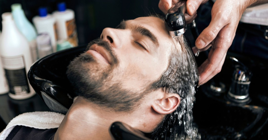 man washing hair in barbershop